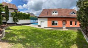 una casa naranja y blanca con un patio verde en Vila dům Emma, en Bořetice