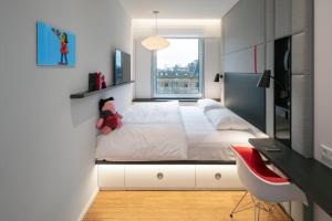 a bedroom with a large white bed and a desk at citizenM Copenhagen Radhuspladsen in Copenhagen