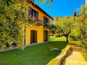 a yellow house with a green yard and trees at Charming Bellagio Boutique Hotel in Bellagio
