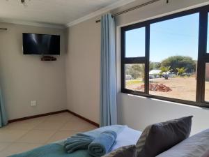 ein Wohnzimmer mit einem TV, einem Sofa und einem Fenster in der Unterkunft Eden Chalets in Windhoek