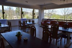 ein Esszimmer mit Tischen und Stühlen und Fenstern in der Unterkunft Pensiunea Daiana in Frasin