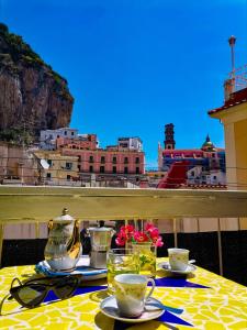einen Tisch mit Teetassen und Gläsern auf dem Balkon in der Unterkunft Francesca House in Atrani