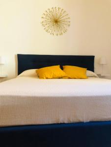 a bed with two yellow pillows and a clock on the wall at Dimora Paladino in Naples
