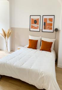a bedroom with a large white bed with orange pillows at Le Petit Nicolas in Les Andelys