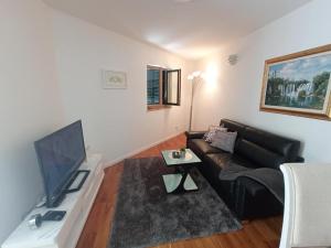 a living room with a black couch and a tv at Sweet suite in Makarska