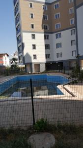 a fence in front of a building with a swimming pool at 1+1 furnished flat with pool in Lara