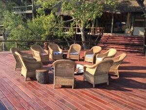 a group of wicker chairs sitting on a deck at Lianshulu Lodge in Kongola