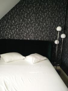 a bedroom with a bed with two pillows and two lamps at B&B VILLA MONIQUE in Koksijde