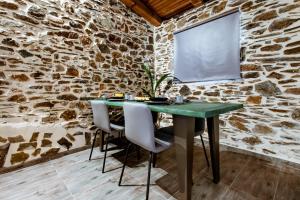 a stone walled dining room with a green table and chairs at Traditional Apartments Elafos in Loúkhiou