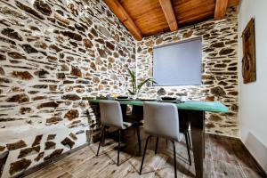 a stone walled dining room with a green table and chairs at Traditional Apartments Elafos in Loúkhiou