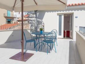 einen Tisch und Stühle auf einem Balkon mit Sonnenschirm in der Unterkunft Odissea Residence e Rooms in Santa Maria di Castellabate