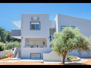 une maison bleue avec un arbre en face dans l'établissement Meliria Apartments, à Skala Rachoniou