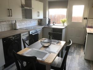 a kitchen with a wooden table with chairs and a table at Rowan Place 5 Bedroom Off Street Parking Accommodation in Durham