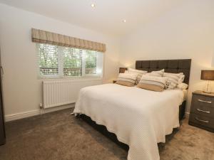 a bedroom with a large white bed and a window at Mere Brook Lodge in Windermere