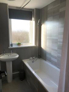 a bathroom with a tub and a sink and a window at Rowan Place 5 Bedroom Off Street Parking Accommodation in Durham