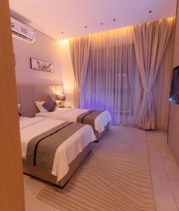 um quarto de hotel com duas camas e uma televisão em فيفيان بارك الروابى Vivian Park Al Rawabi em Riyadh