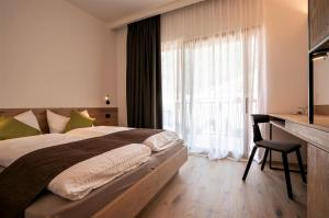 um quarto com uma cama, uma secretária e uma janela em Active Hotel Rosat em Predazzo