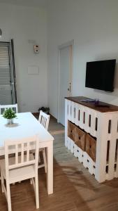 uma sala de estar com uma mesa branca e uma televisão em A casuzza em Marzamemi