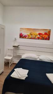Un dormitorio con una cama azul con una pintura en la pared en A casuzza en Marzamemi