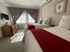 Habitación de hotel con 2 camas y TV en Ngwenya Hotel & Conference Centre, en Klerksdorp