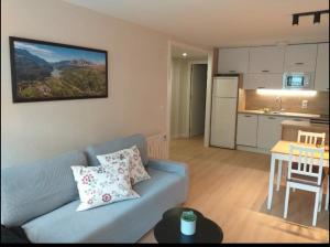 a living room with a blue couch and a kitchen at Apartamento Casa Bielsa in El Pueyo de Jaca