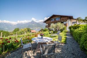 a garden with a table and chairs and a house at Ferienwohnung Cuve in Merano