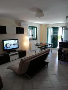 Il comprend un salon doté d'une télévision et d'une table avec des chaises. dans l'établissement Marlen's House, à Bernalda