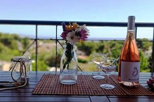 una mesa con una botella de vino y un jarrón con flores en Artemis Penthouse 10 minute from national airport, en Artemida