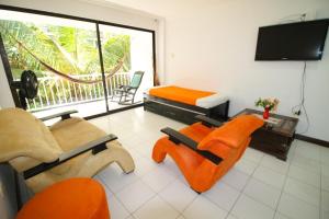 Il comprend un salon avec des chaises orange et une télévision à écran plat. dans l'établissement Patuca Apartamentos By DANP, à Santa Marta