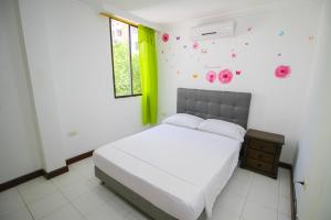 - une chambre avec un lit blanc décoré dans des tons verts et roses dans l'établissement Patuca Apartamentos By DANP, à Santa Marta