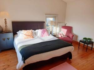 a bedroom with a large bed and a red chair at QUAI 3 loft moderne et lumineux les pieds dans l'eau in Jarnac