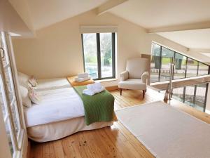 a bedroom with a bed and a chair and a window at QUAI 3 loft moderne et lumineux les pieds dans l'eau in Jarnac