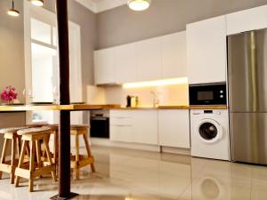 uma cozinha com armários brancos, uma mesa e uma máquina de lavar louça em Casa Lara by HnM em Tavira