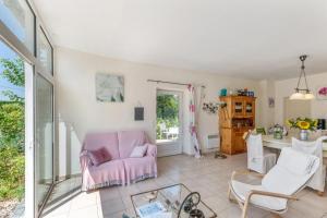 a living room with a pink chair and a table at A L'Orée du Bois in Rétaud