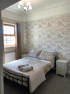 a bedroom with a bed and a wall with wallpaper at 13 Hooton Cottage 3 Bed in Kilnhurst