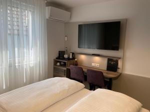 a hotel room with two beds and a television at Hotel Kosel garni, mit tollen Eröffnungspreisen und Europa-Park Eintrittskarten Garantie in Rust