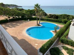 a swimming pool with the ocean in the background at Apartamento en Playa Santo Tomas 1-5 in Es Migjorn Gran
