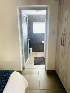 um quarto com uma porta que abre para uma casa de banho com uma cama em Impa-Lala Country Estate em Bloemfontein
