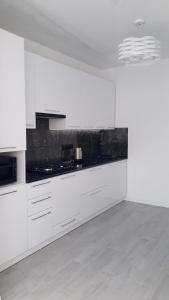 a kitchen with white cabinets and a black counter top at Комфортная квартира по проспекту Коцюбинского , жк Туркиш Сити in Vinnytsya