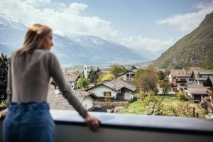 a woman standing on a balcony looking out at the mountains at Hotel Rablanderhof in Rablà