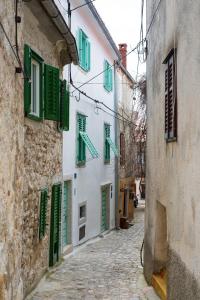 an alley with green shutters on a building at Apartments Bastinica in Krk