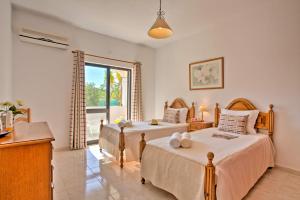 a bedroom with two beds and a window at Villa Candida by Villa Plus in Vale do Lobo +19 photos