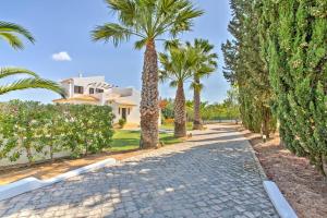 a cobblestone street with palm trees and a house at Villa Candida by Villa Plus in Vale do Lobo