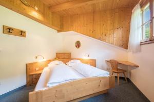 a bedroom with a wooden bed and a desk at Baumgartnerhof Appartment Kornus in Lagundo