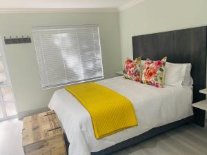a bedroom with a bed with a yellow blanket on it at Impa-Lala Country Estate in Bloemfontein