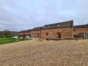 un granero de ladrillo con una mesa de picnic delante de él en Hastings Retreat Rural barn conversions with Private Lake, en Ashby de la Zouch