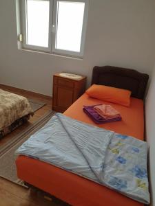 sypialnia z pomarańczowym łóżkiem i oknem w obiekcie Apartment Jelena w Kotorze