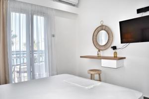 een witte kamer met een bed en een spiegel bij Anagennisi Hotel in Skala