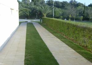 a sidewalk with grass next to a hedge at Casa da Praia Apartment - Alvor Beach in Alvor
