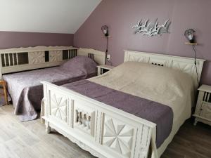 two beds in a bedroom with purple walls at Gîte Hydrangea in Lanhélin